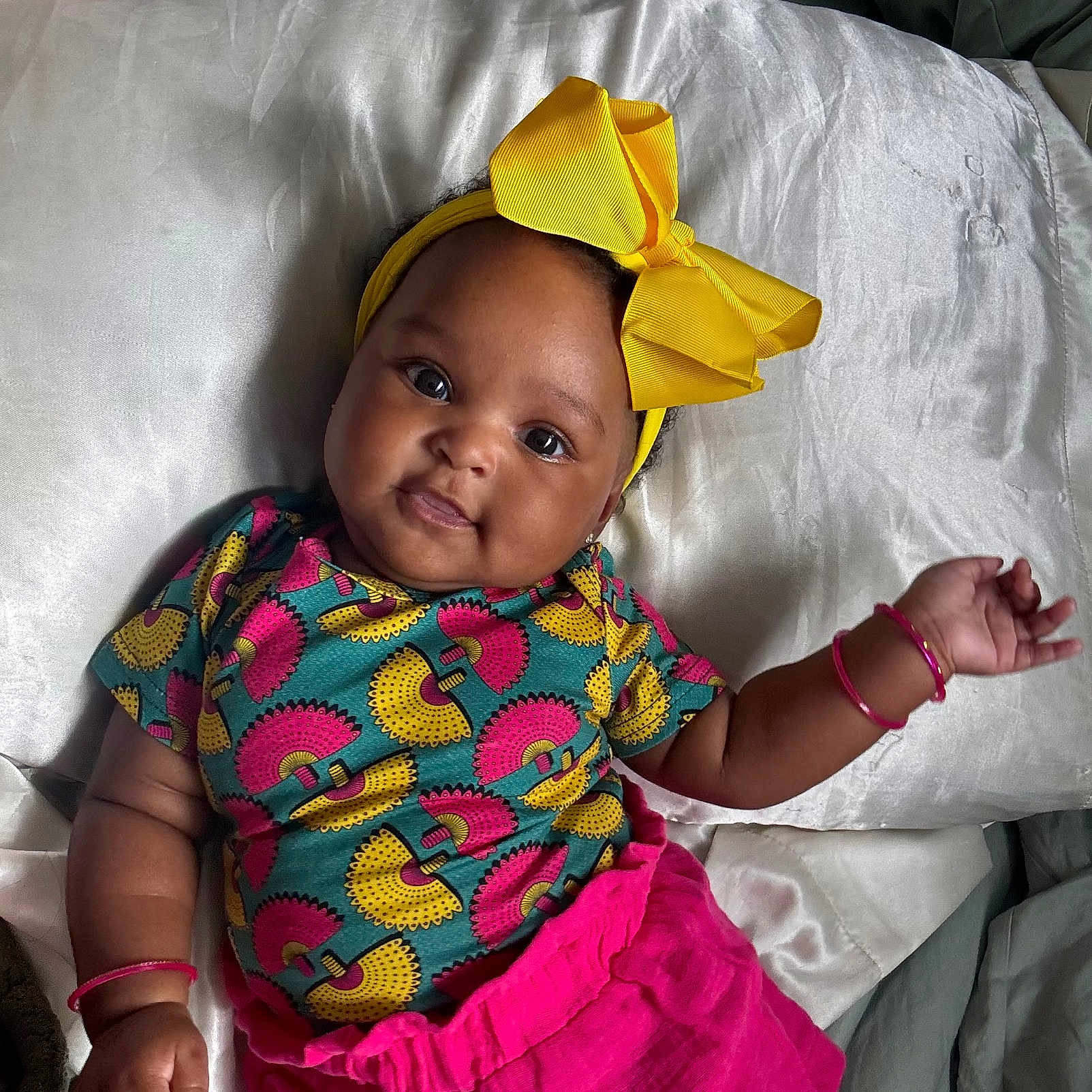 Jade-Rose joined the competition — help win amazing prizes! adorable, baby, bracelets, child, colorful_clothing, cute, face, happy, headband, indoors, infant, lying_down, person, pillow, pink_skirt, portrait, silk, skin, smiling, yellow_bow