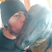 Samantha a rejoint le concours — aidez-le/la à gagner de superbes lots ! man, dog, beanie, kiss, close_up, indoor, window, affection, pet, tongue, casual_clothing, portrait, face, blur, warm_light, animal, friendship, furry, love, headwear