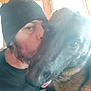 man, dog, beanie, kiss, close_up, indoor, window, affection, pet, tongue, casual_clothing, portrait, face, blur, warm_light, animal, friendship, furry, love, headwear