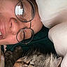 Leo Pickle is registered to the contest to win money with this photo: person, face, glasses, nose_ring, smile, cat, tabby_cat, fur, whiskers, blanket, cozy, close_up, indoor, resting, snuggling, eyewear, eyebrows, skin, head, comfort