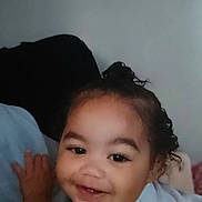 Miah'Ja is registered to the contest to win money with this photo: baby, baby_girl, child, close_up, curly_hair, cute, expression, face, happy, head, human, indoors, infant, light_blue_clothing, person, portrait, skin, smiling, toddler, young_child