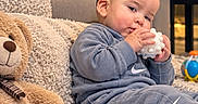 Jaysel joined the competition — help win amazing prizes! baby, child, infant, sitting, indoors, living_room, blanket, couch, teddy_bear, toy, teether, smiling, portrait, blue_clothing, tracksuit, nike_logo, playroom, soft_furnishings, colorful_toy, cozy