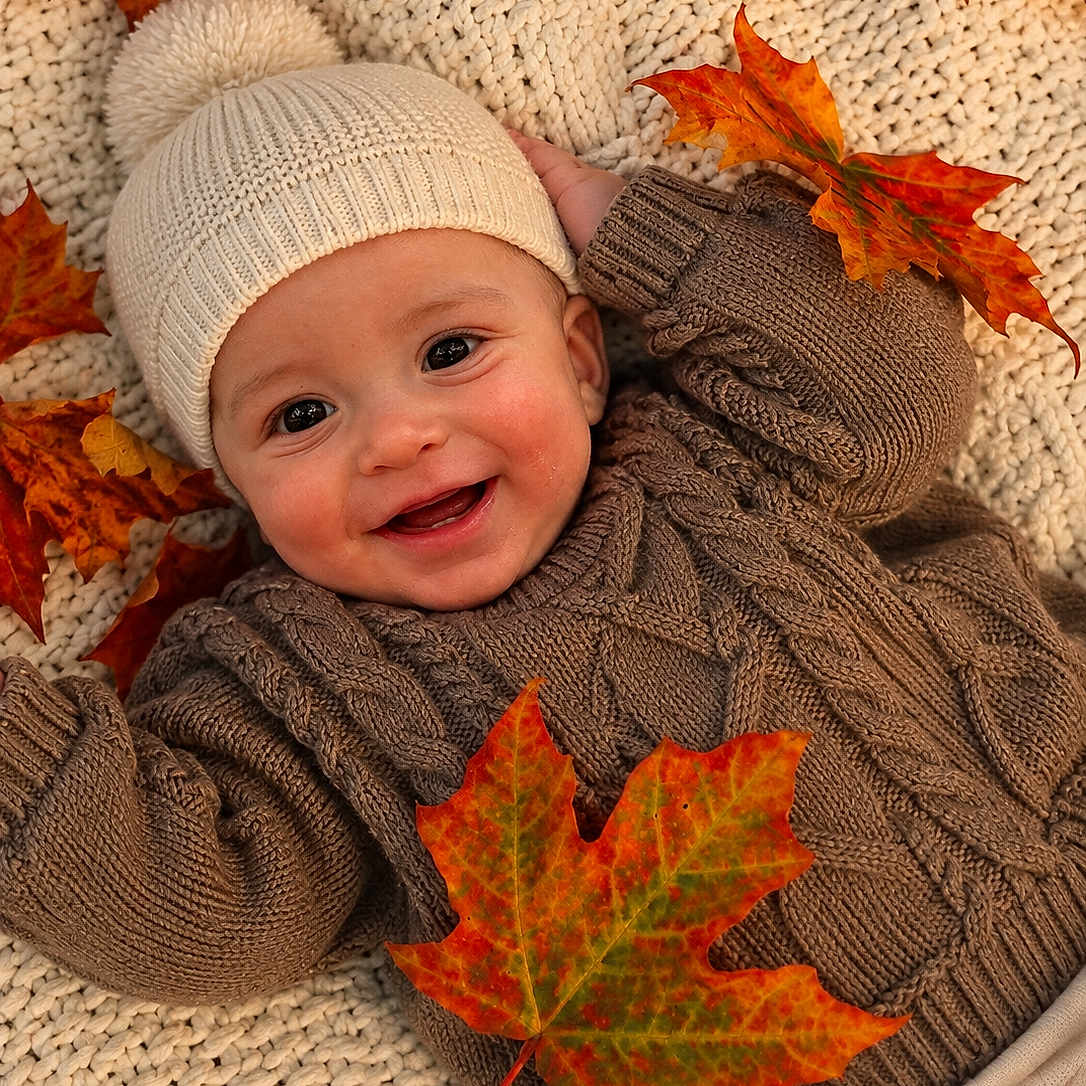 Jaysel is registered to the contest to win money with this photo: baby, child, infant, smiling, portrait, autumn, fall, maple_leaves, knit_hat, winter_clothing, sweater, blanket, cozy, lying_down, close_up, indoor, warm_colors, seasonal, happy, photography