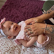 Ariana joined the competition — help win amazing prizes! adult_hands, baby, bracelet, fingers, floor, happy, headband, indoor, infant, laughing, person, pink_clothing, playful, polka_dot_mat, purple_carpet, ring, skin, smiling, striped_wall, tattoos