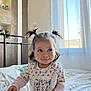 Dunja a rejoint le concours — aidez-le/la à gagner de superbes lots ! toddler, child, pigtails, bed, indoor, curtains, window, natural_light, smile, playful, person, clothing, long_sleeves, floral_pattern, home, cozy, portrait, cute, young_child, happy