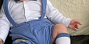 Justin is registered to the contest to win money with this photo: baby, child, infant, sitting, couch, leather, pillow, white_shirt, blue_suspender, blue_shorts, socks, cute, expression, indoor, furniture, person, portrait, young, skin, head