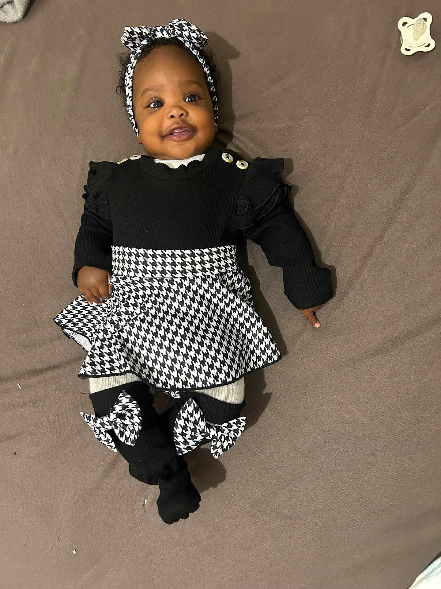 Lalyah participe au concours pour gagner de l'argent avec cette photo : baby, child, smiling, headband, black_clothing, white_clothing, houndstooth_pattern, bow, lying_down, bed, blanket, happy, cute, infant, fashion, sock, toddler, portrait, person, indoors