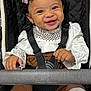 baby, child, smiling, curly_hair, bow, stroller, seatbelt, white_clothing, brown_clothing, knit_socks, happy, cute, infant, portrait, indoors, person, baby_girl, fashion, accessory, comfort