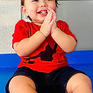 Nathan joined the competition — help win amazing prizes! baby, blue_floor, child, clapping, cute, face, floor, hair, hands, happy, indoor, joy, person, portrait, red_shirt, shorts, sitting, skin, smiling, toddler