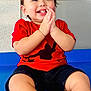 baby, blue_floor, child, clapping, cute, face, floor, hair, hands, happy, indoor, joy, person, portrait, red_shirt, shorts, sitting, skin, smiling, toddler