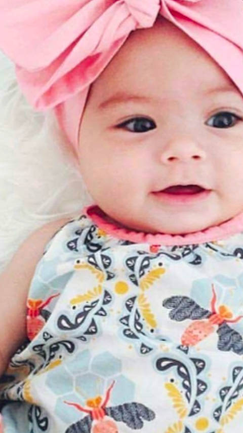 Emerson is registered to the contest to win money with this photo: baby, beauty, cheek, child, child_model, face, hair_accessory, head, headgear, lip, mouth, nose, pattern, person, pink, skin, smile, toddler