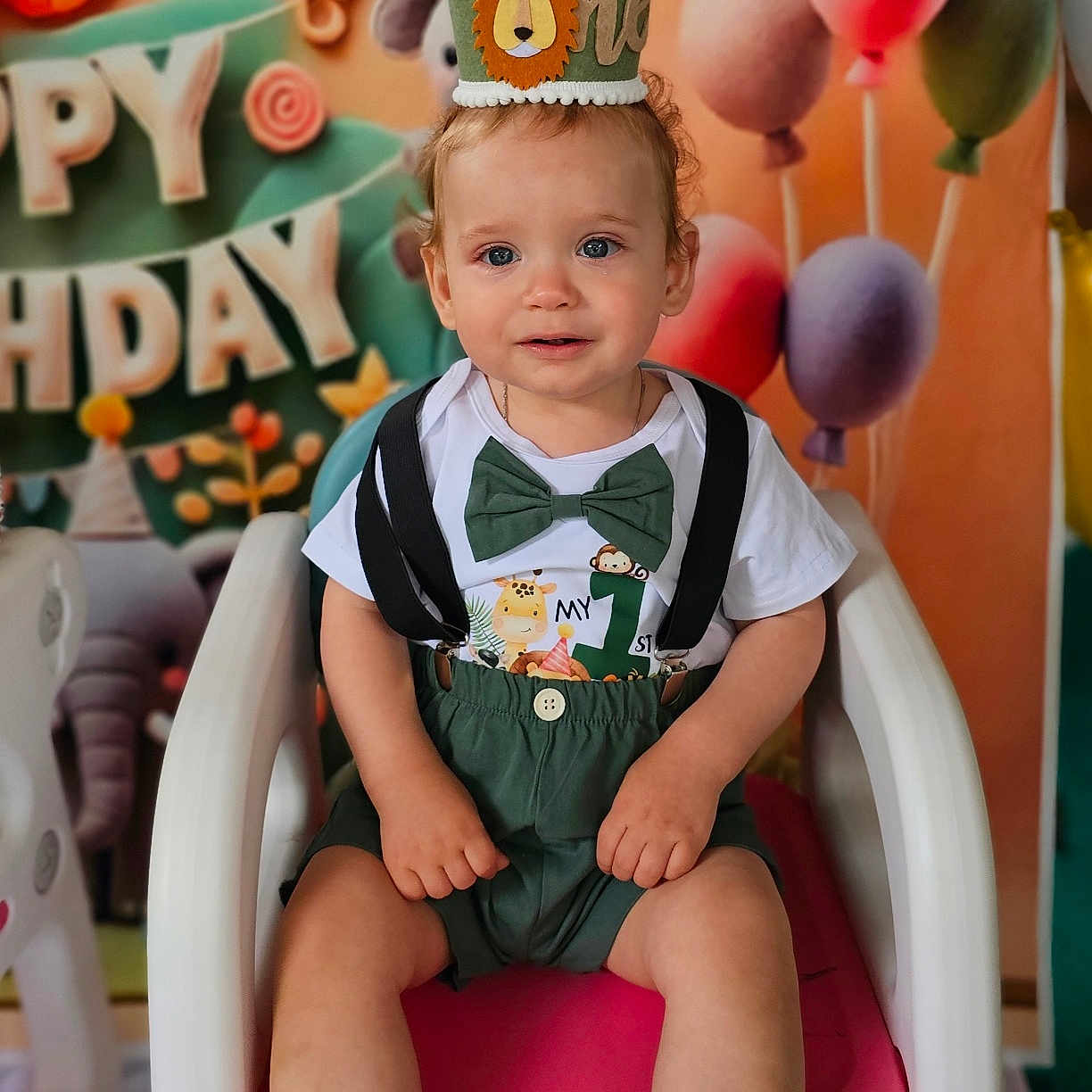 Constatin is registered to the contest to win money with this photo: background, balloons, birthday, bow_tie, celebration, chair, child, crown, cute, decorations, first_birthday, green_clothing, happy, indoor, monkey, party, pink_chair, smiling, suspenders, toddler