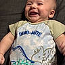 Stetson is registered to the contest to win money with this photo: baby, infant, child, smiling, laughing, portrait, face, eyes, mouth, dinosaur, dinosaur_clothing, onesie, shirt, cushion, indoor, lying_down, happy, close_up, photograph, safe