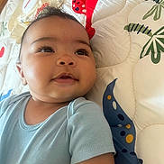 Jaylen joined the competition — help win amazing prizes! baby, infant, child, face, eyes, smile, blue_clothing, onesie, quilt, pattern, colorful, soft_texture, lying_down, cute, closeup, indoor, young, adorable, skin, head