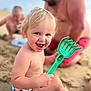 barefoot, beach, blond_hair, blue_eyes, child, family, fun, happy, outdoor, person, play, rake, relaxation, sand, smile, summer, sunlight, toddler, toy, vacation