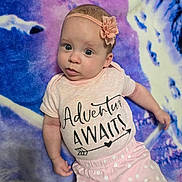 Emily joined the competition — help win amazing prizes! baby, infant, wide_eyes, headband, flower_headband, pink_onesie, text_on_shirt, polka_dot_pants, blanket, purple_background, blue_background, lying_down, portrait, cute, small_hand, skin, staring, soft_texture, nursery, indoors