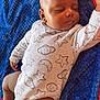 baby, sleeping, onesie, stars, moon, blue_blanket, pacifier, red_socks, blue_socks, cartoon_character, infant, cute, child, resting, indoors, soft_texture, peaceful, clothing, person, toddler