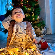 Tao participe au concours pour gagner de l'argent avec cette photo : toddler, child, baby, smiling, sitting, fairy_lights, christmas_tree, holiday, indoor, cozy, blanket, cat, decorations, warm_lighting, cute, festive, happy, clothing, floor, toy