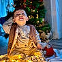 toddler, child, baby, smiling, sitting, fairy_lights, christmas_tree, holiday, indoor, cozy, blanket, cat, decorations, warm_lighting, cute, festive, happy, clothing, floor, toy