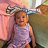 Skyla is registered to the contest to win money with this photo: baby, child, smiling, purple_dress, flamingo_pattern, couch, green_couch, pink_hoodie, indoor, happy, person, infant, seated, portrait, home, furniture, cute, young_child, sitting, casual_clothing