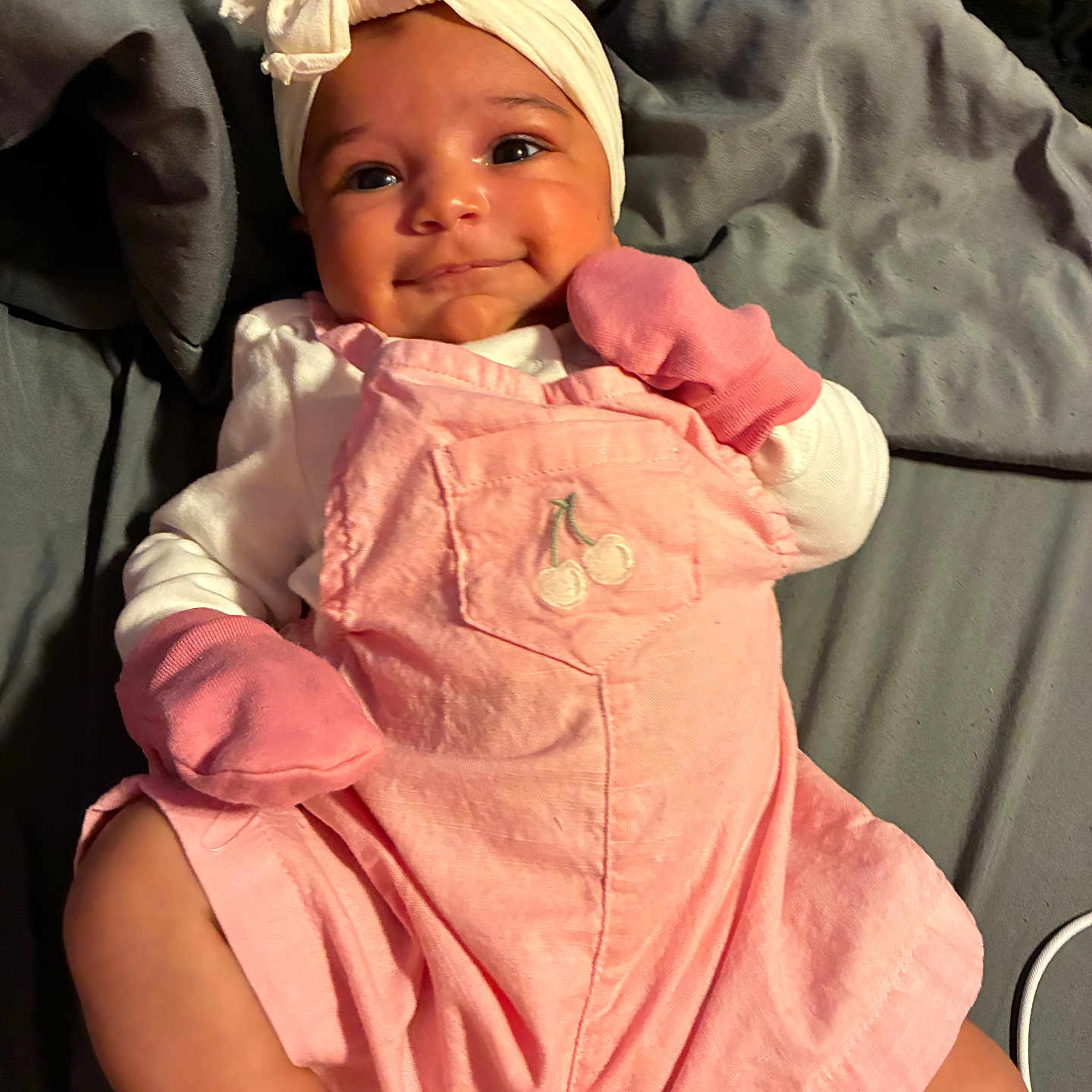 Skyla joined the competition — help win amazing prizes! baby, infant, smile, pink_clothing, mittens, headwrap, bow, blanket, cute, child, lying_down, soft_texture, closeup, adorable, face, happy, cherry_embroidery, white_socks, indoor, portrait