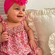 Ova a rejoint le concours — aidez-le/la à gagner de superbes lots ! baby, blue_eyes, child, cute, dress, fabric, floral_pattern, flower, hand, happy, headwear, indoors, infant, pillow, pink_headband, portrait, ruffled_pillow, seated, skin, smiling