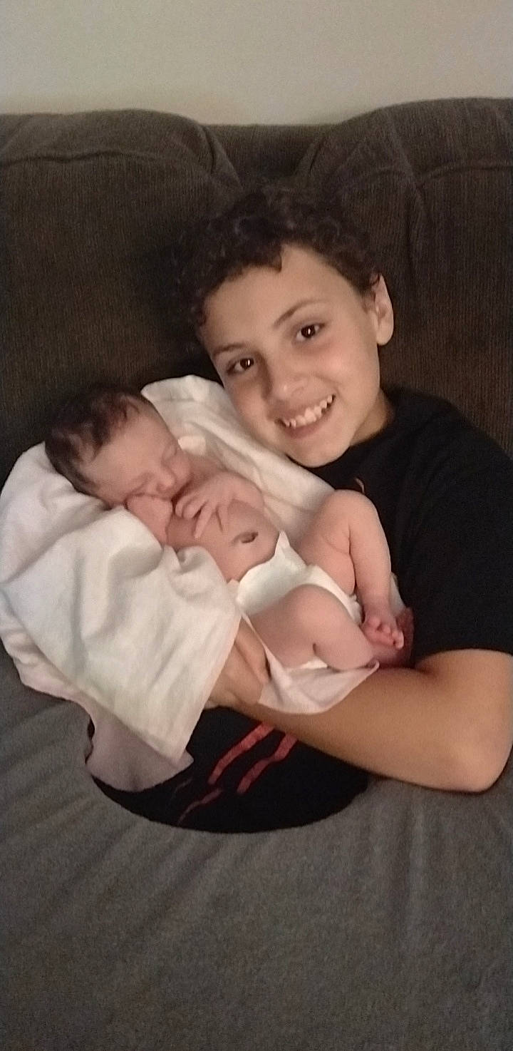 Caleb is registered to the contest to win money with this photo: abdomen, arm, baby, baby_toddler_clothing, cheek, child, comfort, elbow, eye, flash_photography, fun, gesture, hand, happy, iris, joy, linens, person, sitting, sleeve