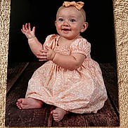 Harlow is registered to the contest to win money with this photo: baby, child, smiling, clapping, dress, headband, bow, floor, wooden_floor, portrait, sitting, cute, happy, infant, female, studio, photography, black_background, skin, foot