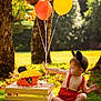 toddler, child, birthday_cake, balloons, outdoor, grass, trees, sunlight, red_clothing, headband, mickey_mouse_ears, wooden_crate, celebration, nature, fall_leaves, park, cute, baby, summer, playful