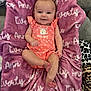 baby, infant, smiling, pink_outfit, blanket, text, couch, indoor, cute, child, face, person, leopard_print, plush_blanket, happy, comfort, portrait, sitting, soft_texture, cozy