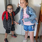 Jimmy participe au concours pour gagner de l'argent avec cette photo : backpack, casual_clothing, child, children, denim_jacket, door, elevator, floor, glasses, happy, indoor, person, playful, portrait, shorts, smiling, sneakers, standing, wall, young