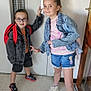 backpack, casual_clothing, child, children, denim_jacket, door, elevator, floor, glasses, happy, indoor, person, playful, portrait, shorts, smiling, sneakers, standing, wall, young