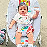 Zayvion joined the competition — help win amazing prizes! baby, child, infant, baby_rocker, outdoor, concrete, grass, white_shoes, shorts, tshirt, serious_expression, colorful, seat, toy, pacifier_clip, legs, feet, summer_clothing, person, cute