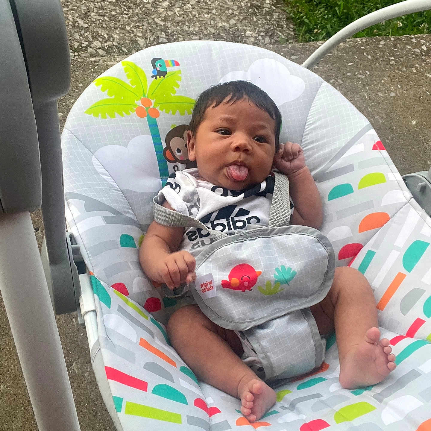 Zayvion joined the competition — help win amazing prizes! baby, infant, baby_seat, tongue_out, colorful, patterned, outdoor, concrete, grass, cute, cheeky, child, person, seat, playful, young, toddler, clothing, expression, resting