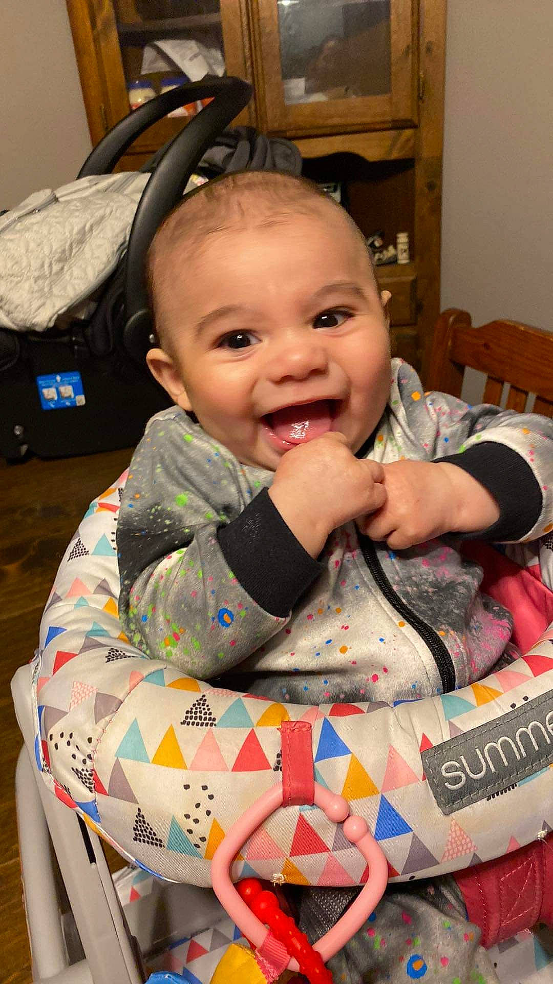Maxwell is registered to the contest to win money with this photo: baby, baby_carriage, baby_products, baby_toddler_clothing, bag, box, cabinetry, cheek, child, event, fun, happy, head, iris, luggage_and_bags, person, room, shelf, sitting, smile