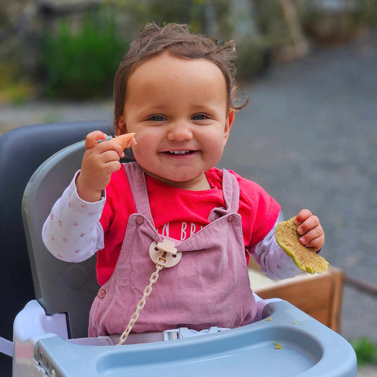 Odélya participe au concours pour gagner de l'argent avec cette photo : baby, child, clothing, cute, daylight, face, food, hands, happy, high_chair, outdoor, person, pink_overalls, playful, portrait, red_shirt, seat, smiling, toddler, young_child