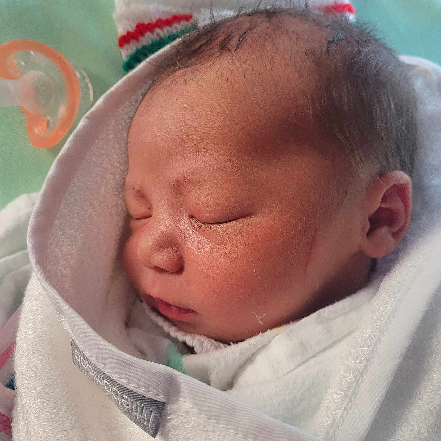 Aiden is registered to the contest to win money with this photo: baby, blanket, bonnet, clothing, face, hat, head, hood, hoodie, knitwear, newborn, person, photography, portrait, quilt, sleeping, sweater, sweatshirt, towel
