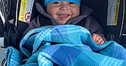 Giovanni joined the competition — help win amazing prizes! baby, blanket, blue, blue_hat, car_seat, child, clothing, cozy, cute, face, footwear, happy, indoor, infant, person, portrait, seat, smiling, toddler, warm