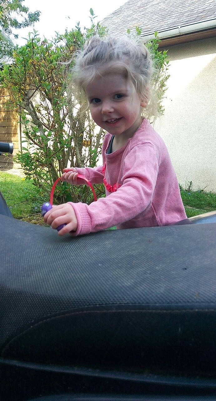 Anaé participe au concours pour gagner de l'argent avec cette photo : automotive_exterior, baby_toddler_clothing, child, eye, fun, garden, grass, happy, head, joy, leisure, magenta, person, pink, plant, recreation, sitting, smile, toddler, trampolining_equipment_and_supplies