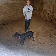 Jazzmine joined the competition — help win amazing prizes! animal, black_dog, casual_clothing, cave, curious, dim_light, dirt_floor, dog, exploration, footwear, hoodie, indoor, leash, leisure, orange_collar, person, pet, rock_wall, standing, walking