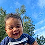baby, smiling, child, outdoor, sky, blue_sky, trees, greenery, happy, person, face, holding, toddler, short_hair, casual_clothing, blue_shirt, daylight, nature, portrait, cute