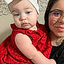 Diamantina is registered to the contest to win money with this photo: baby, child, woman, glasses, red_dress, headband, bow, tattoo, face, skin, hand, holding, portrait, indoor, person, smile, apparel, accessory, young_child, family