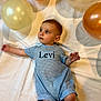 Levi joined the competition — help win amazing prizes! baby, infant, romper, blue_clothing, balloon, gold_balloon, cream_balloon, white_sheet, laying_down, curious, child, portrait, indoor, soft_lighting, cute, small_feet, short_hair, looking_away, peaceful, one_person