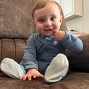 Levi is registered to the contest to win money with this photo: baby, child, infant, blue_outfit, couch, sofa, brown_couch, indoor, cute, smiling, hand, fingers, face, eyes, sitting, plush, cozy, playful, young_child, portrait