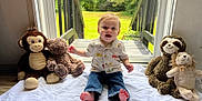 Levi joined the competition — help win amazing prizes! toddler, child, indoor, plush_toys, monkey, bear, sloth, lion, white_sheet, glass_door, green_lawn, happy, smiling, casual_clothing, jeans, short_sleeve_shirt, barefoot, natural_light, cute, playtime