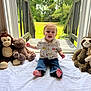 toddler, child, indoor, plush_toys, monkey, bear, sloth, lion, white_sheet, glass_door, green_lawn, happy, smiling, casual_clothing, jeans, short_sleeve_shirt, barefoot, natural_light, cute, playtime