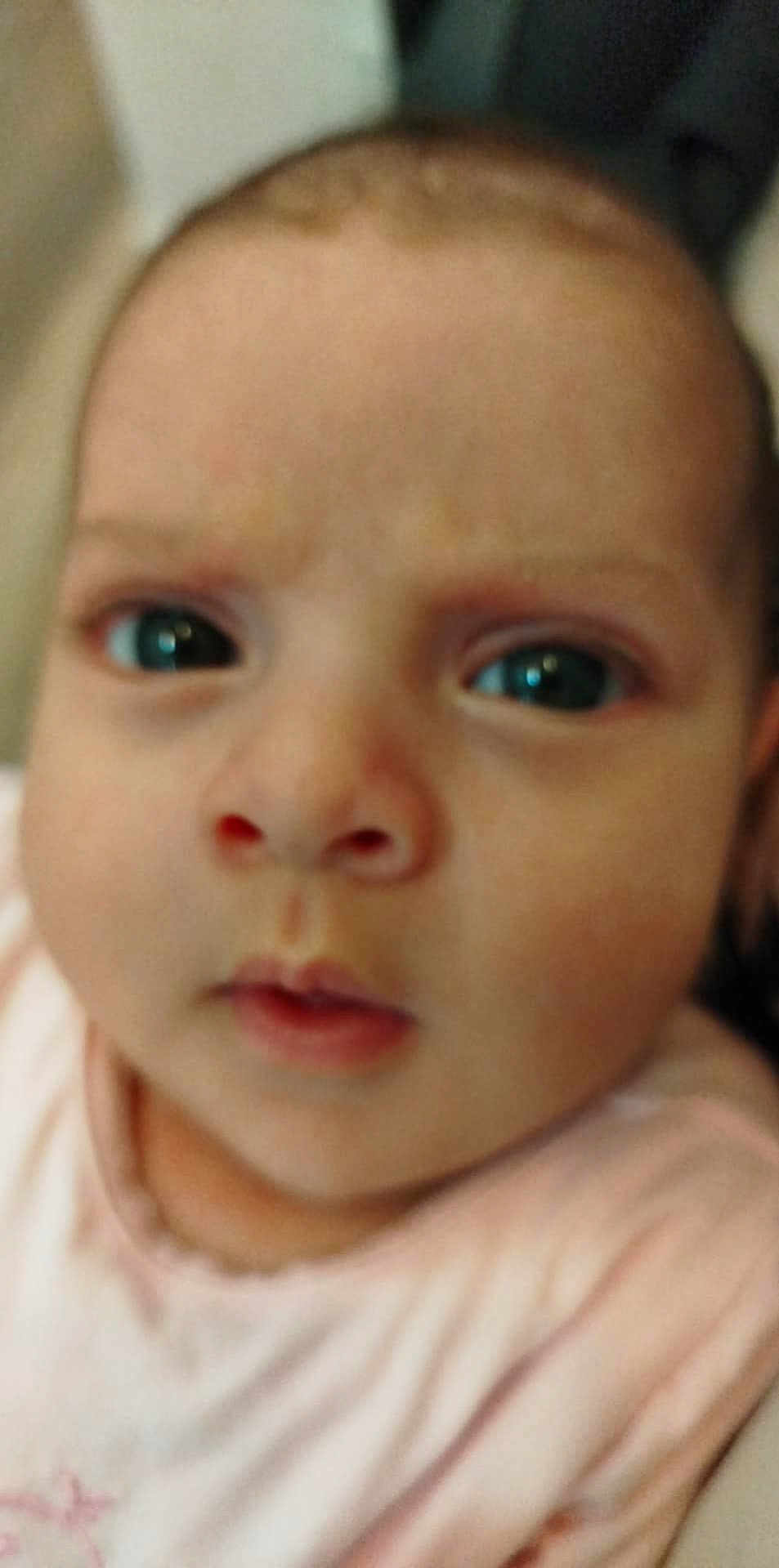 Amira participe au concours pour gagner de l'argent avec cette photo : baby, face, closeup, child, infant, pink_clothing, expression, person, skin, head, eyes, mouth, nose, young, indoors, portrait, unfocused, cute, soft, human