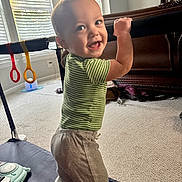 Jacob joined the competition — help win amazing prizes! toddler, child, smiling, standing, playpen, mesh, green_shirt, grey_pants, indoor, daylight, window, blinds, carpet, furniture, toy, happy, person, baby, home, cute