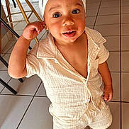 Braydenn participe au concours pour gagner de l'argent avec cette photo : toddler, child, indoor, bandana, white_clothing, crocs, tile_floor, curious_expression, standing, light_outfit, plant, chair, home, smiling, person, casual_wear, young_child, cute, portrait, happy