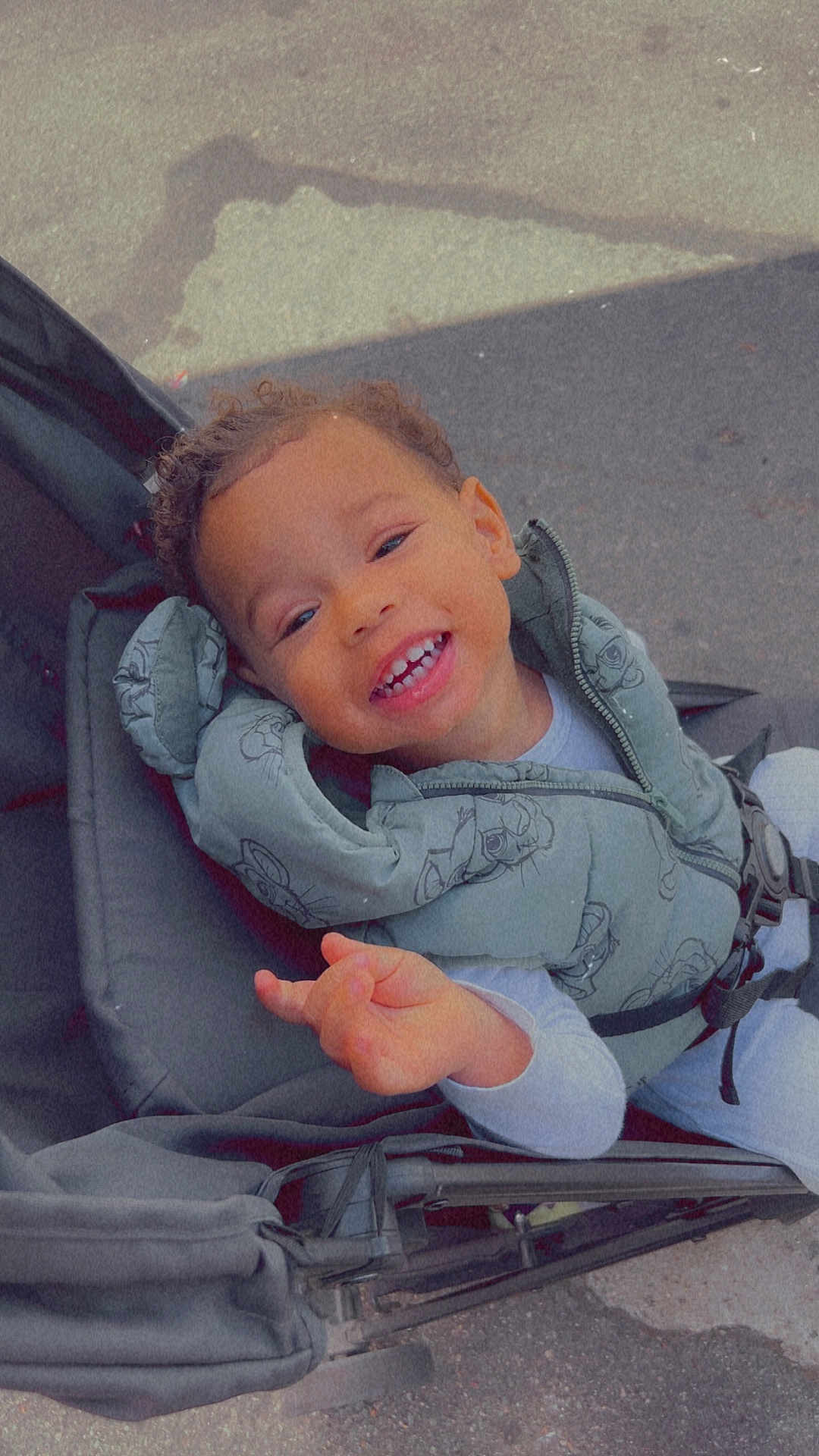 Braydenn a rejoint le concours — aidez-le/la à gagner de superbes lots ! toddler, child, smiling, stroller, jacket, curly_hair, outdoor, happy, cute, baby, person, seat, clothing, playful, young_child, portrait, casual, daylight, baby_wear, expression